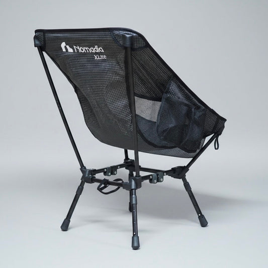 Black camping chair with mesh back and 'Nomad' branding on a gray background