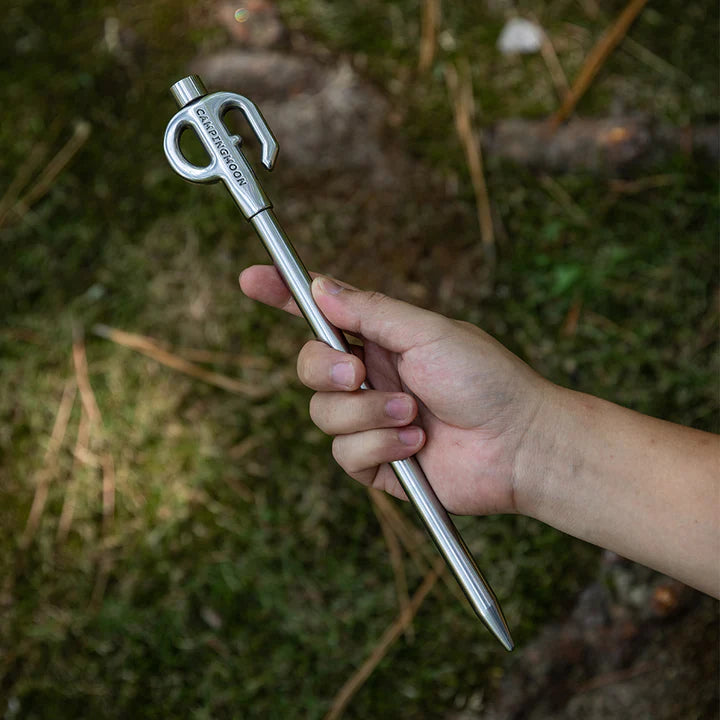 Hand holding a Nomadia Accessory Camp Peg for Pet against a natural background - camping gear - uk camping