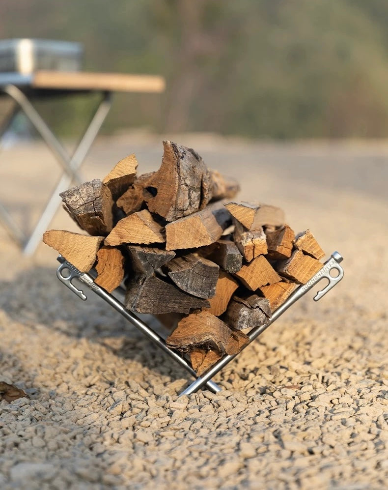 Stack of chopped wood with Nomadia Accessory Forged Camp Pegs on a gravel surface - multi-use - multi purpose - camping gear - camping essential