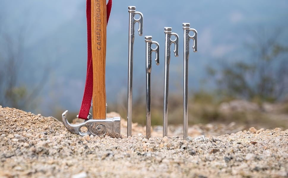 Nomadia Accessory Forged Camp Pegs with a wooden stake driver on a rocky surface - camping gear - wildcamping