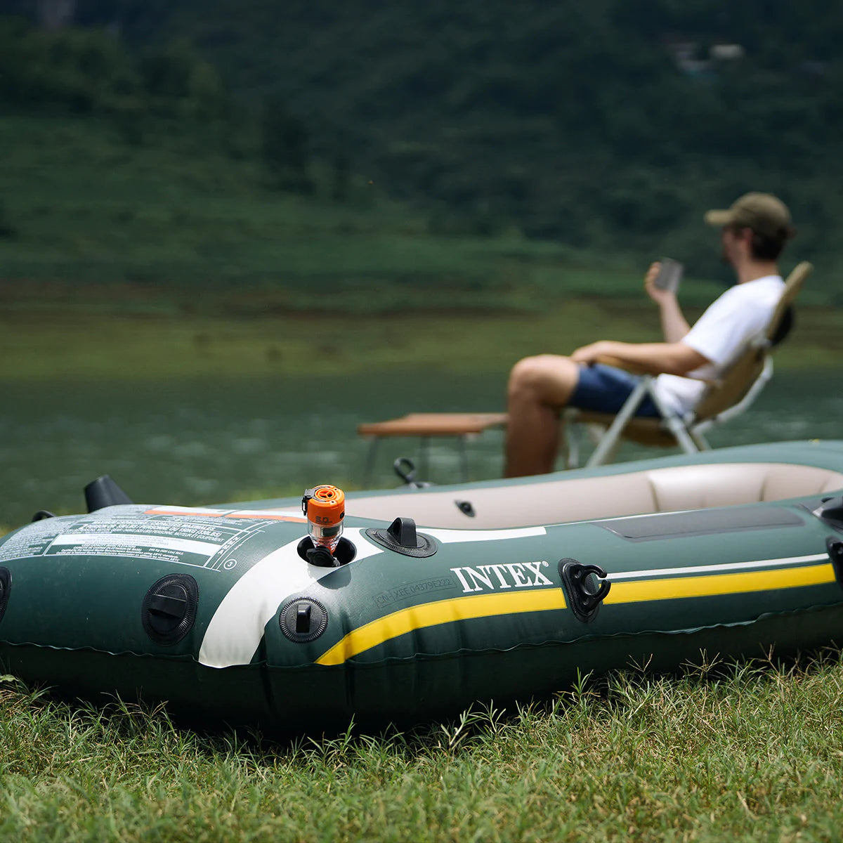 using Nomadia Accessory High Speed 2-in-1 Rechargeable Air Pump to inflate a boat on while the person sit on the background - powerful air pump -camping essential