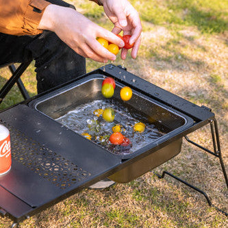 person washing fruits with Nomadia CampStation Kitchen Sink on a modular camping table outdoor