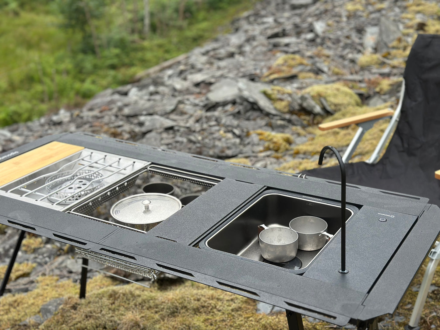 Portable outdoor modular camping table setup with Nomadia CampStation Kitchen Sink, stove set and pots on a natural background