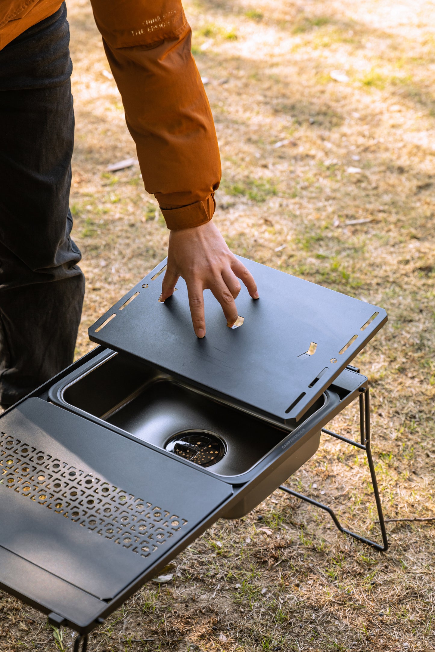 person putting a modular board on top of Nomadia CampStation Kitchen Sink so it can be used as a platform - camping gear - modular fit - glamping
