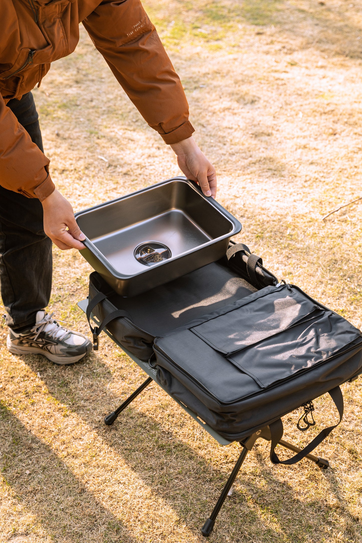 person placing Nomadia CampStation Kitchen Sink into storage bag - portable camping gear - outdoor cooking equipment - easy storage