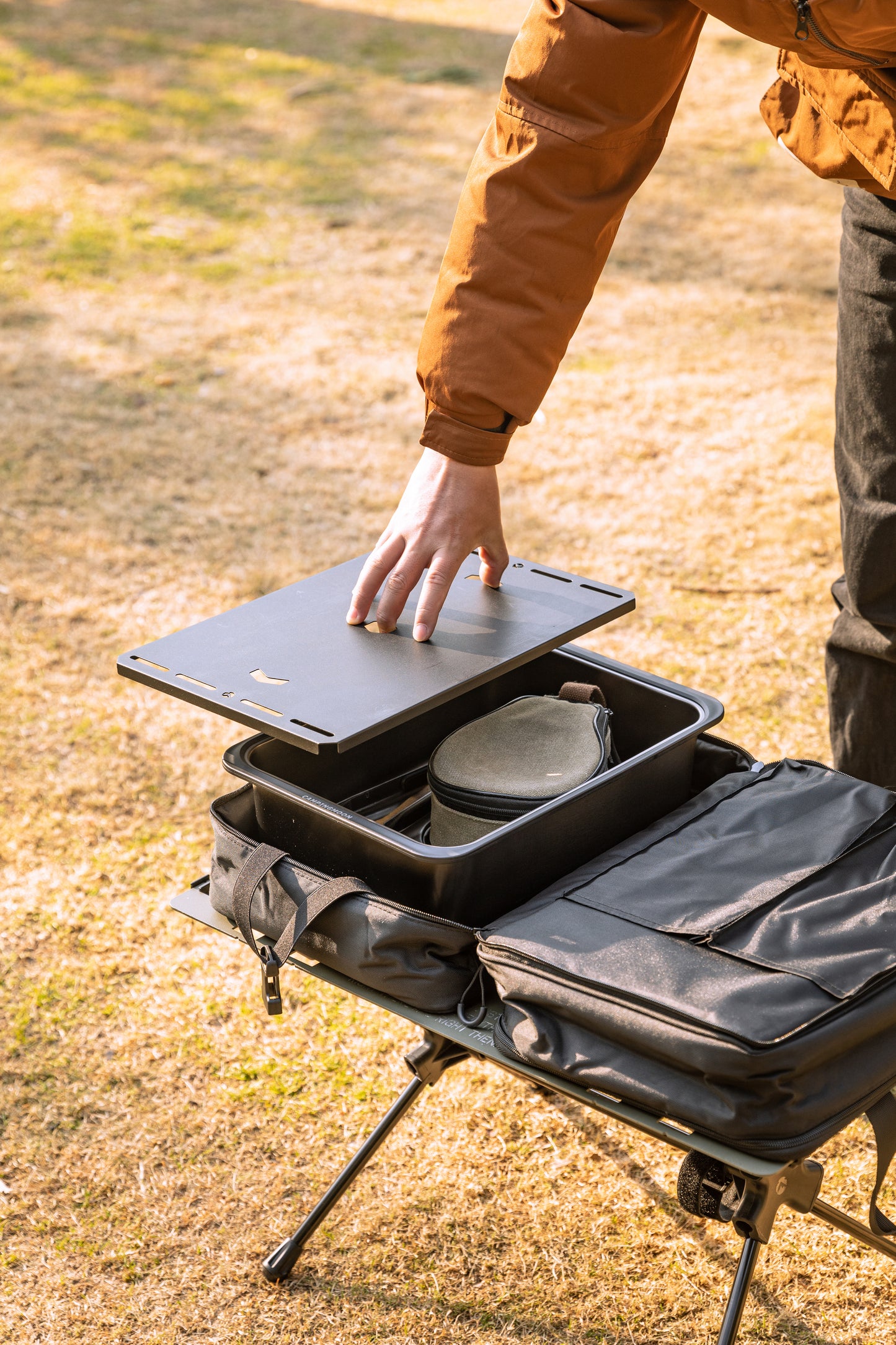 person putting Nomadia CampStation Kitchen Sink into storage bag - easy storage - portable camping gear - outdoor cooking equipment - glamping