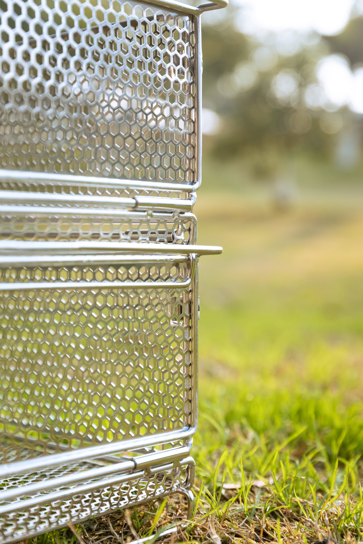 close up of two metal mesh basket stacked together on grass with natural background - stackable - multi purpose - wildcamping