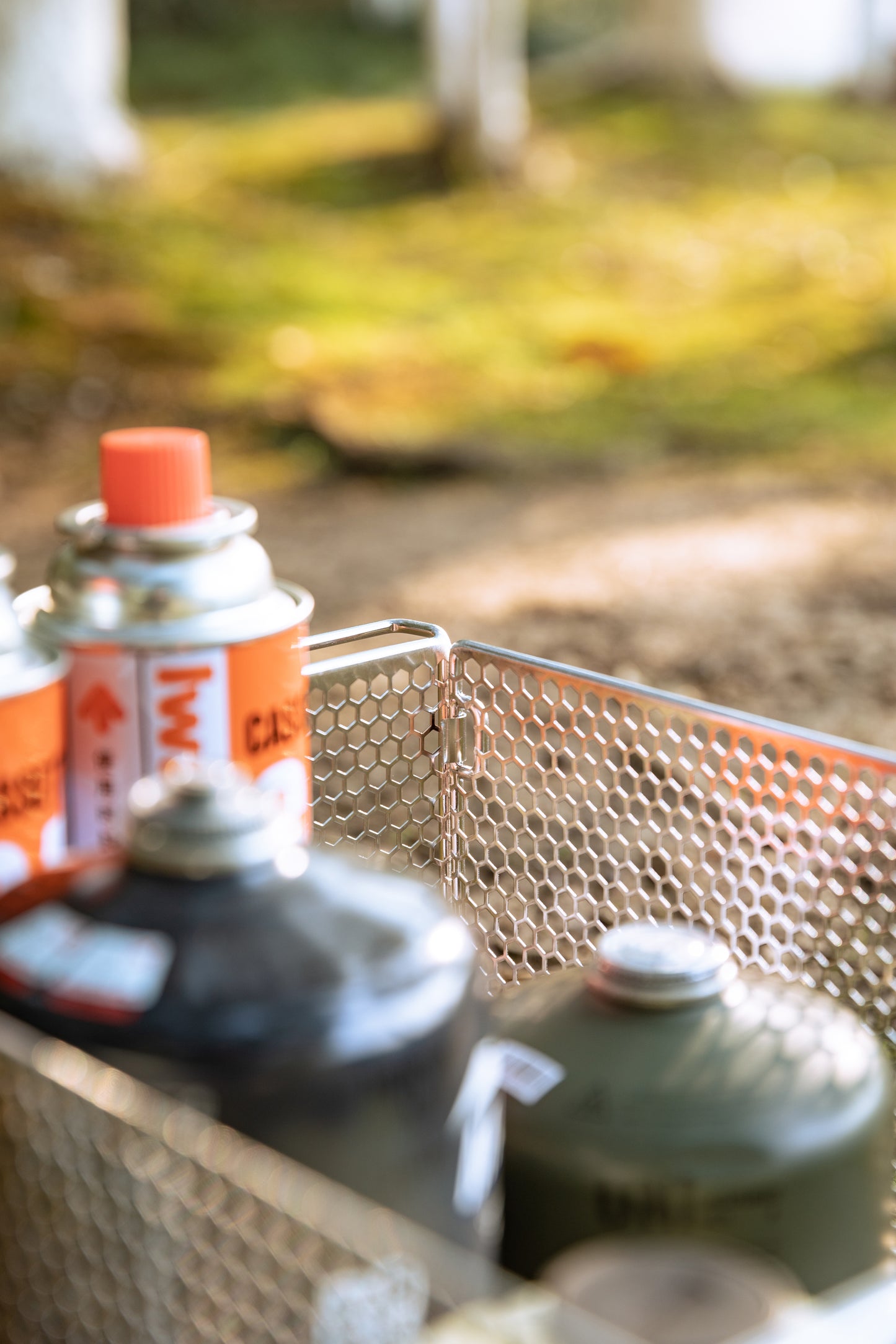 various sized gas canisters on a mesh basket with a forest background - wild camping - camping gear - uk camping