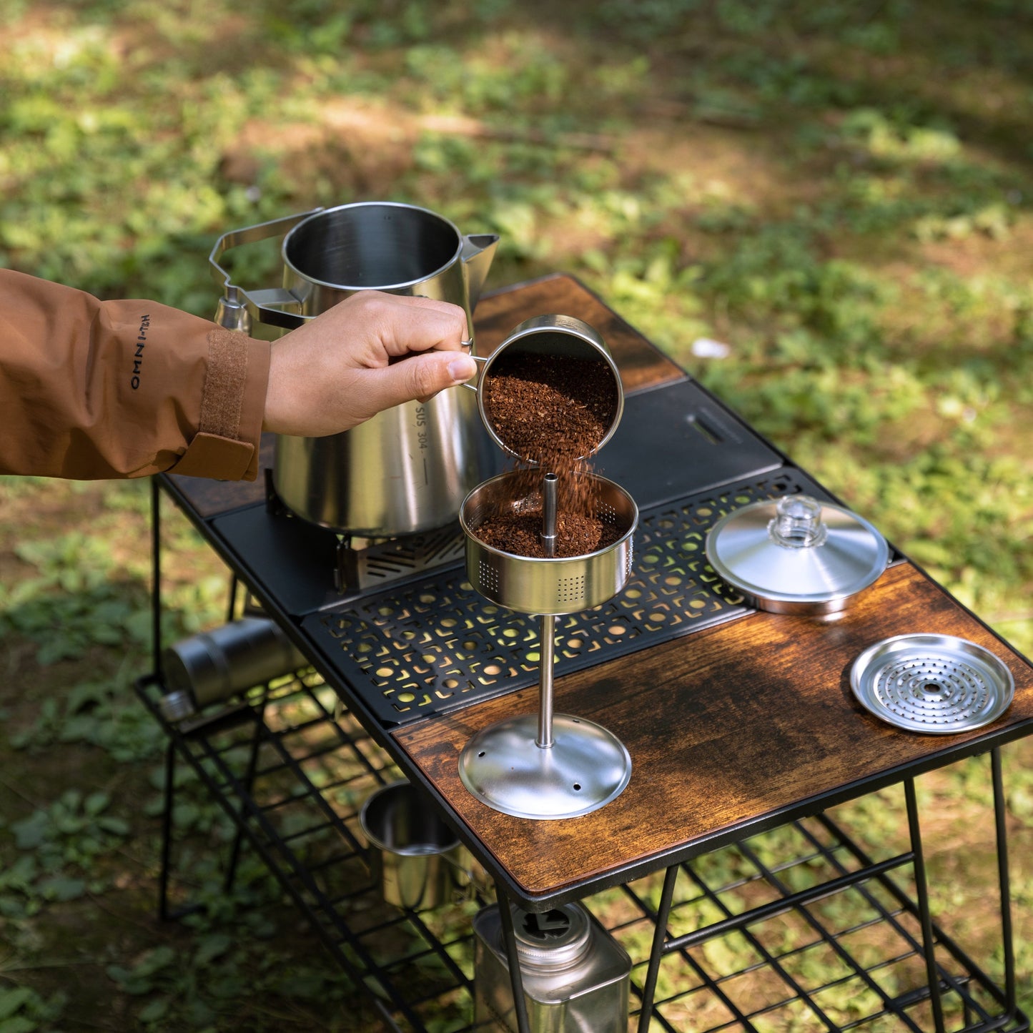 Person preparing coffee outdoors using a portable stove and coffee maker Nomadia CampStation Stainless Steel Coffee Pot - outdoor cooking equipment - outdoor coffee maker