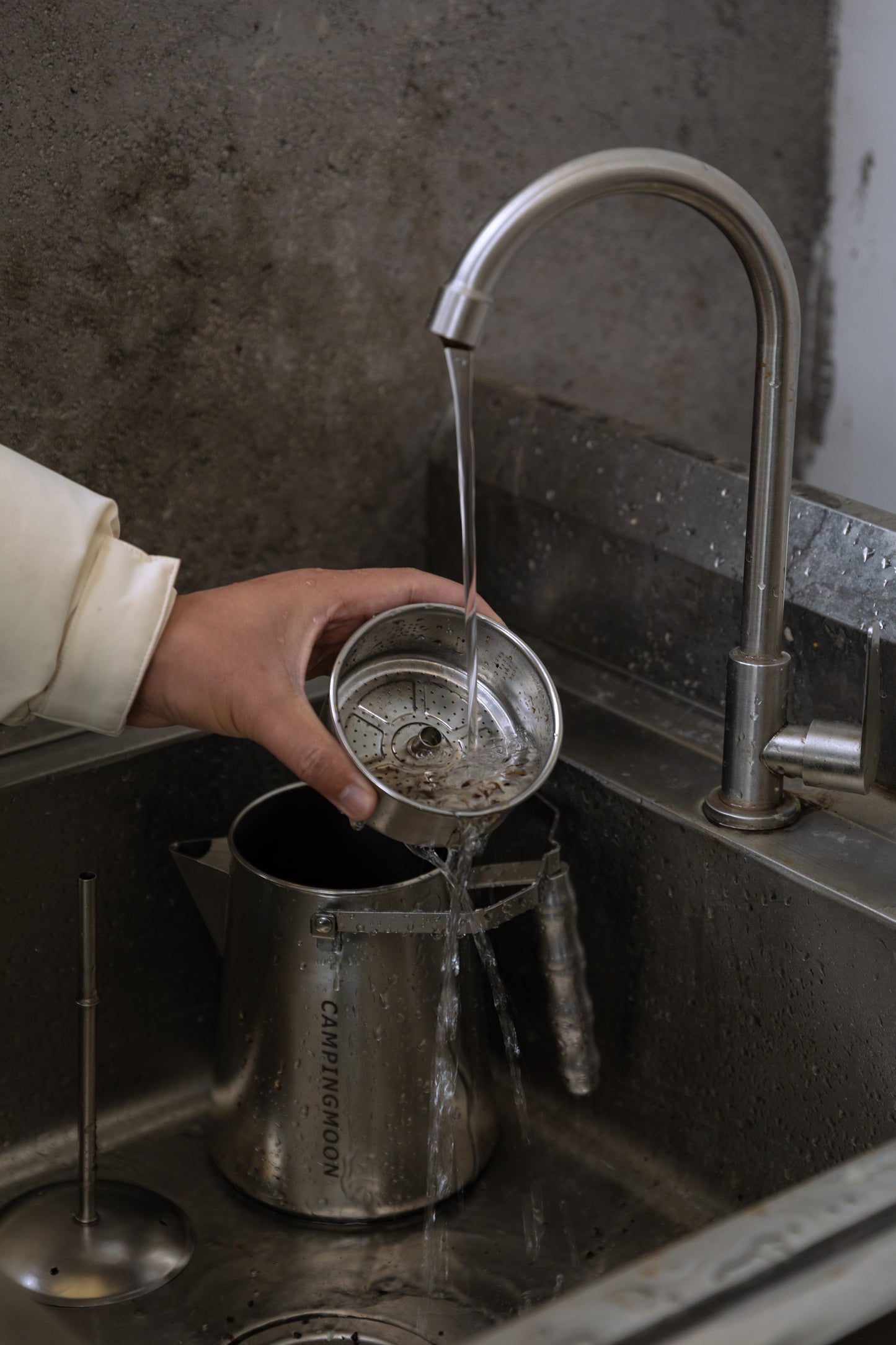 Person washing a metal coffee filter from Nomadia CampStation Stainless Steel Coffee Pot under running water in a kitchen sink - uk camping - outdoor cooking equipment