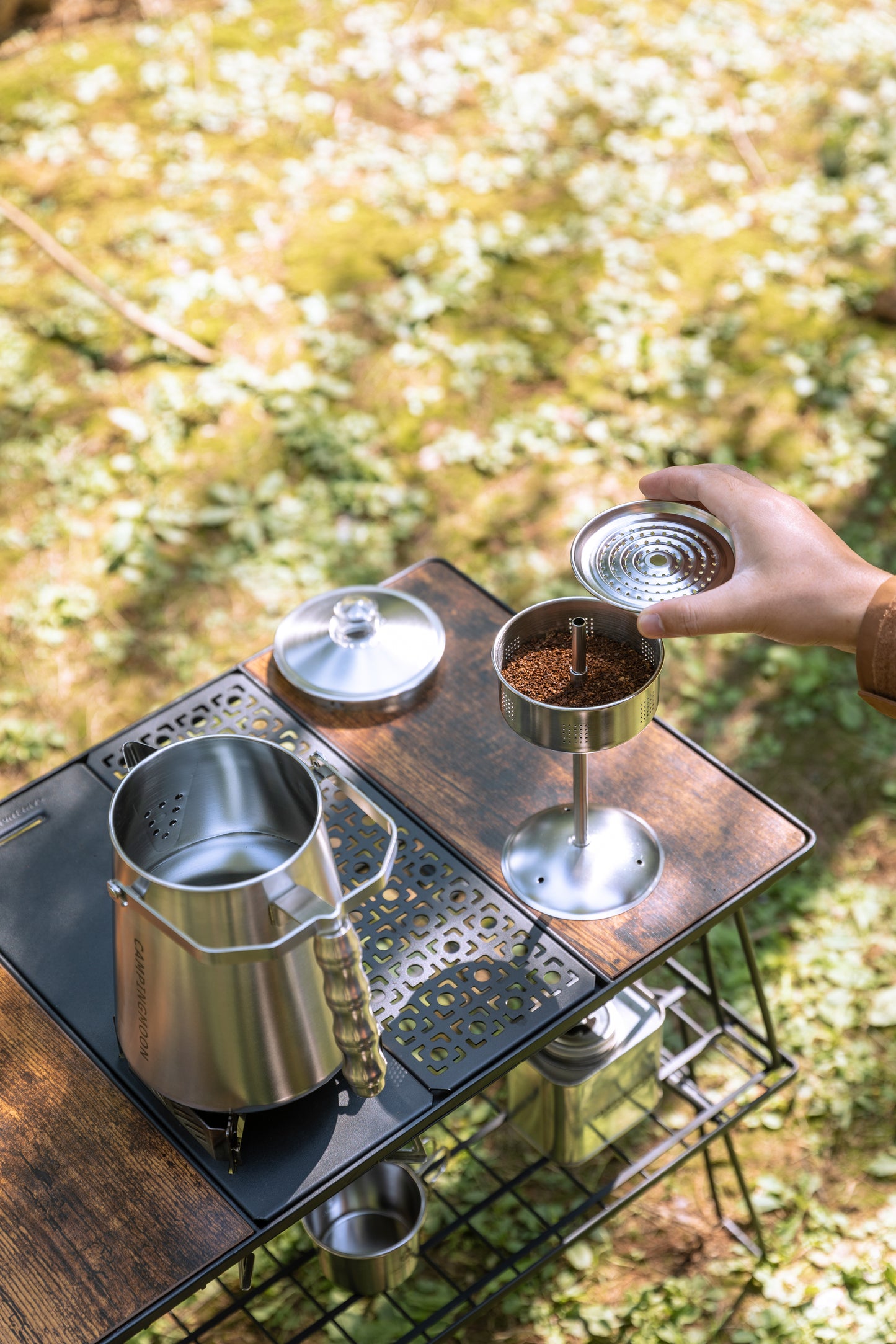 Person preparing coffee outdoors using a portable stove and coffee maker Nomadia CampStation Stainless Steel Coffee Pot - glamping - outdoor cooking equipment