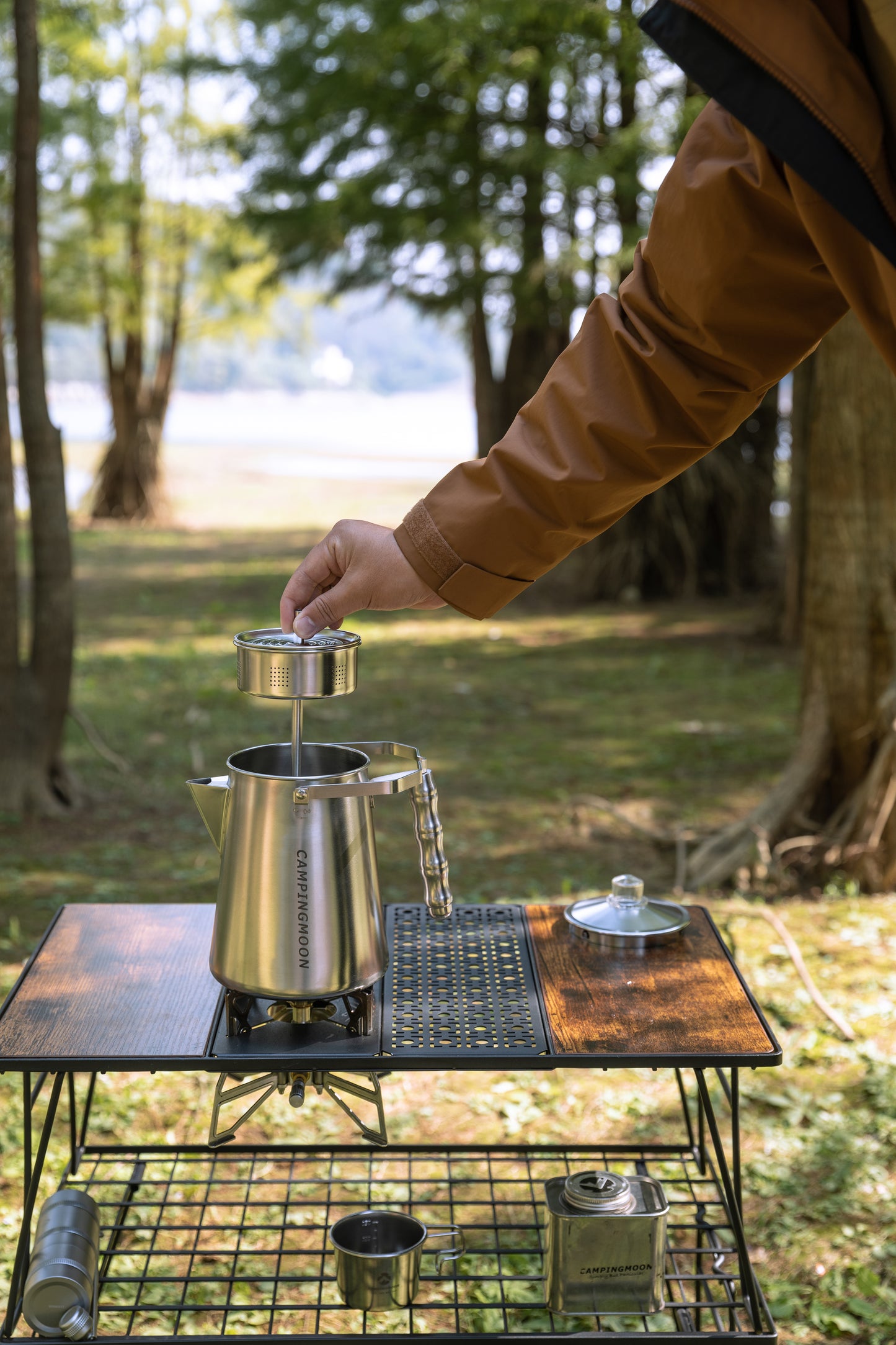 Person preparing coffee outdoors on a camping stove using Nomadia CampStation Stainless Steel Coffee Pot - outdoor coffee maker - outdoor cooking equipment - glamping