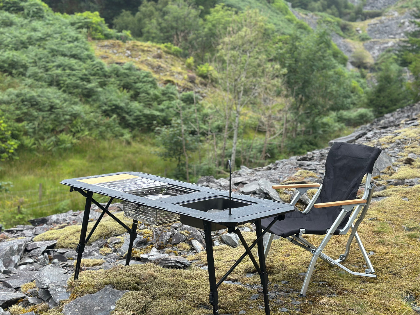 Portable - Folding - Heavy Duty - Compact - Camping Table - Table Set -Modular Flexibility - Modular Camping Table - water dispenser - stainless steel coffee pot - stove set - sink - mesh basket - camping - lifestyle - rocky terrain - wood -relaxing - camping chair
