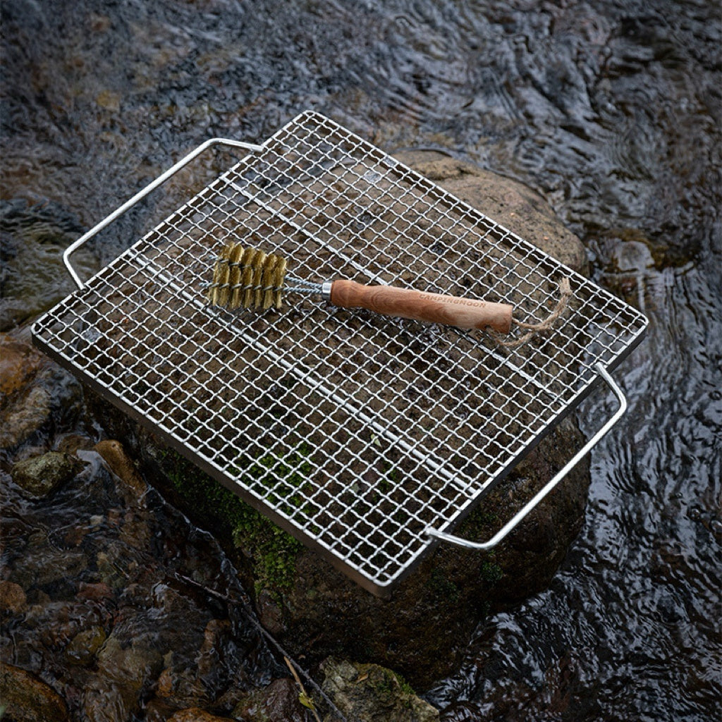 Metal grill grid with Nomadia Flamo 360° BBQ Grill Brush on a stone surface - bbq grill accessory - camping essential - uk camping