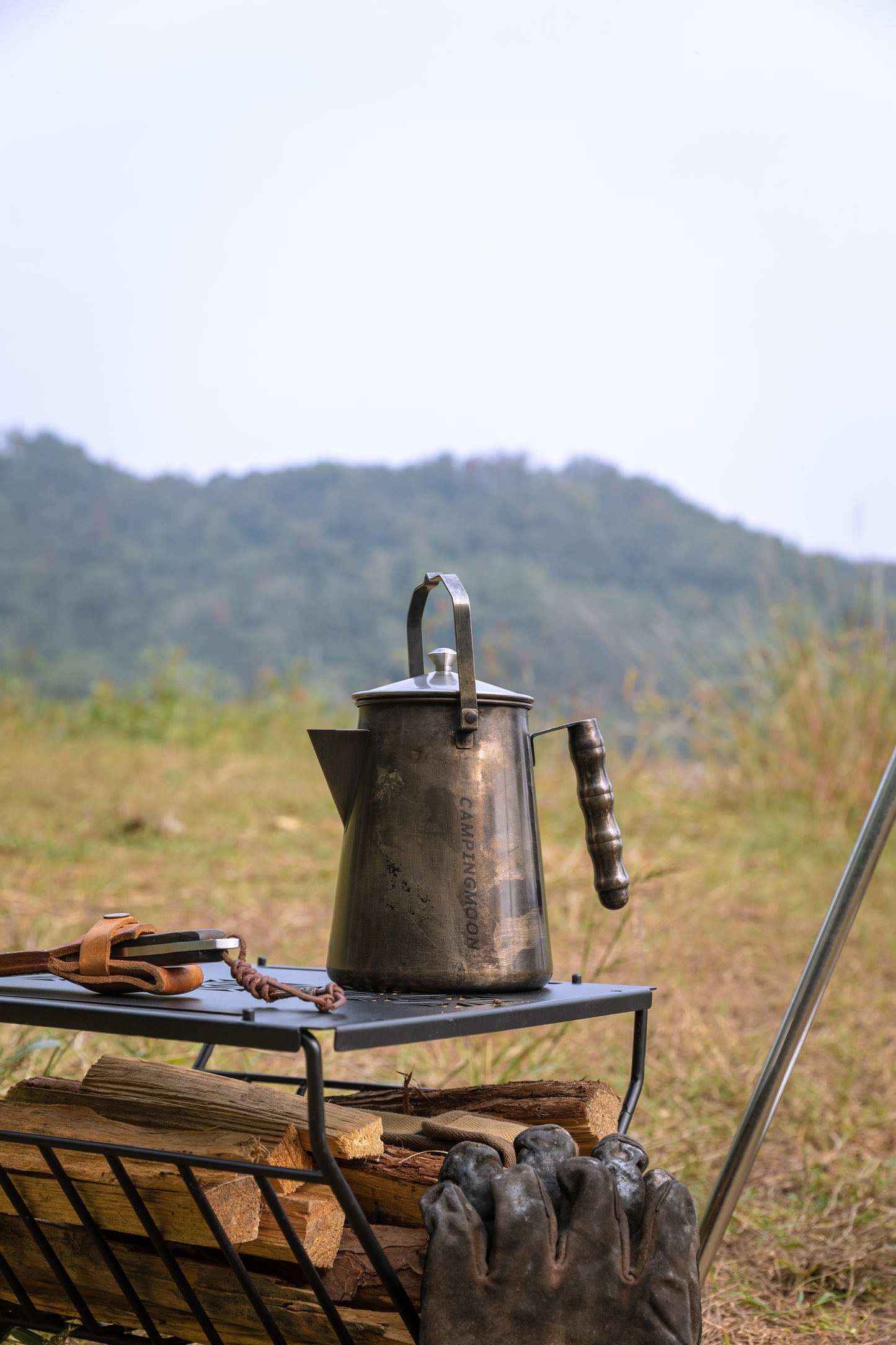 Vintage-style Nomadia Flamo Crafted Camping Kettle metal kettle on a camping stove with a mountainous landscape - wild camping- uk camping