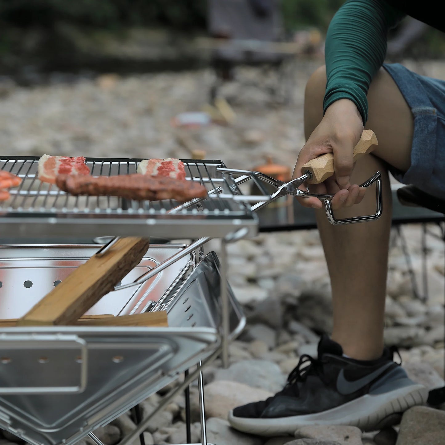 Person grilling food on Nomadia's Flamo Portable Folding BBQ Grill and Fire Pit - wildcamping - camping with a fire - uk camping