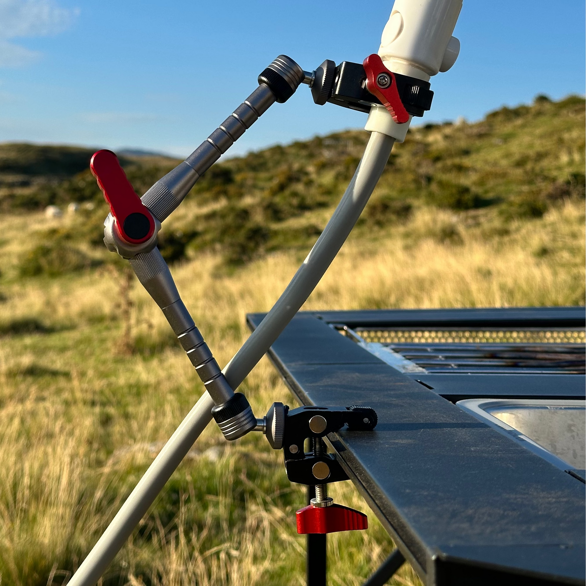 Nomadia FlexArm Dual Clamp used to hold shower head from thermoflow and table for easy showing outdoor - multi-use camping gear