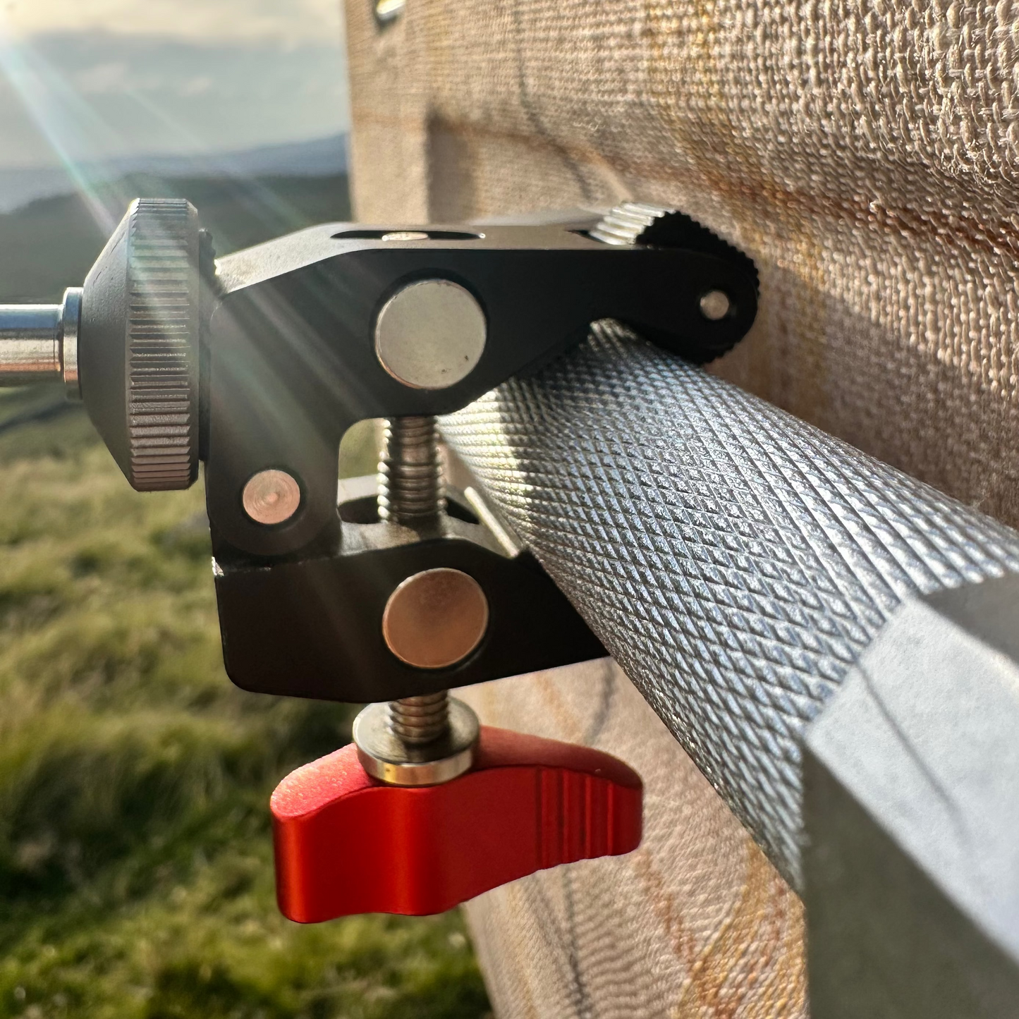 Close-up of a clamp attached to a textured surface Nomadia FlexArm Dual Clamp - multi-surface fit -camping and survival