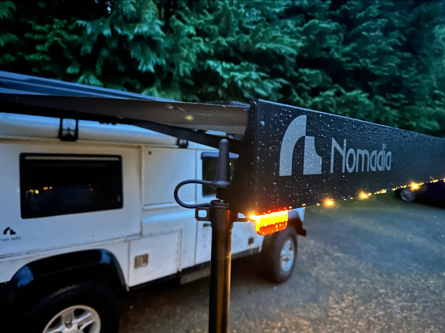 Nomada brand awning extended on a vehicle with trees - overlanding - wildcamping - aluminium awning - easy setup - fast setup awning - all weather durability