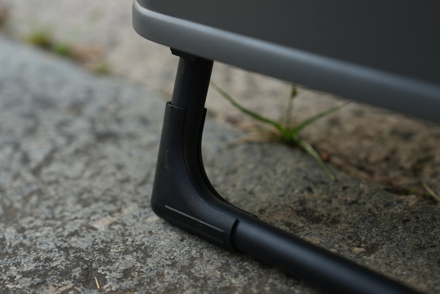 Close-up of a black metal stand on Nomadia ModoBox 2in1 camping table and storage box on rough surface - camping gear - glamping - uk camping