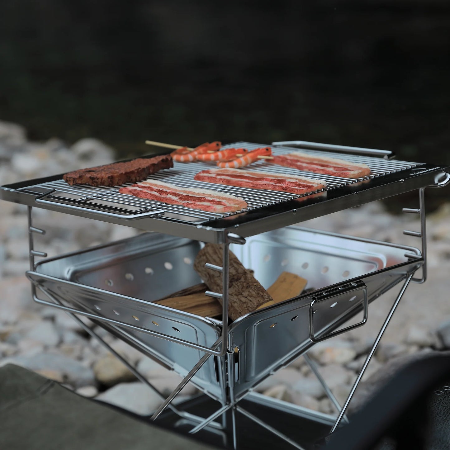 Nomadia's Flamo Portable Folding BBQ Grill and Fire Pit with food being cooked on a natural outdoor setting - wildcamping - camping with a fire - uk camping