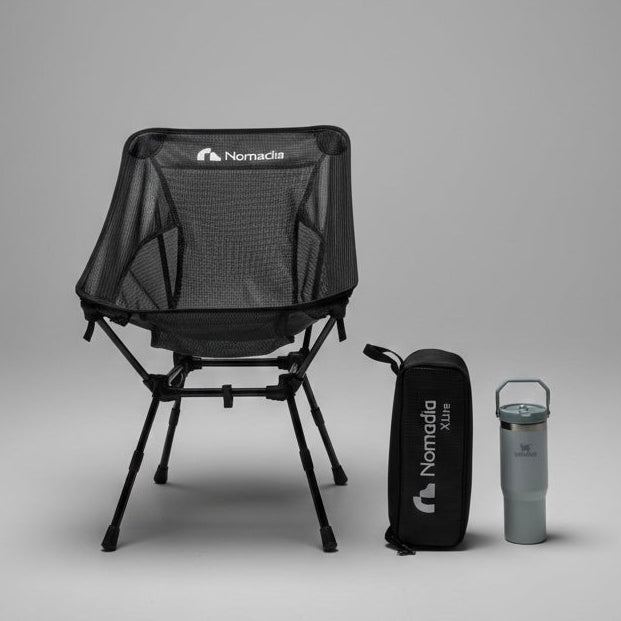 Black camping chair with carrying bag and tumbler on a gray background