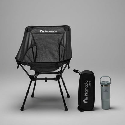 Black camping chair with carrying bag and tumbler on a gray background
