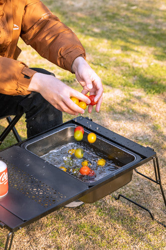 person washing fruits with Nomadia CampStation Kitchen Sink on a modular camping table outdoor 