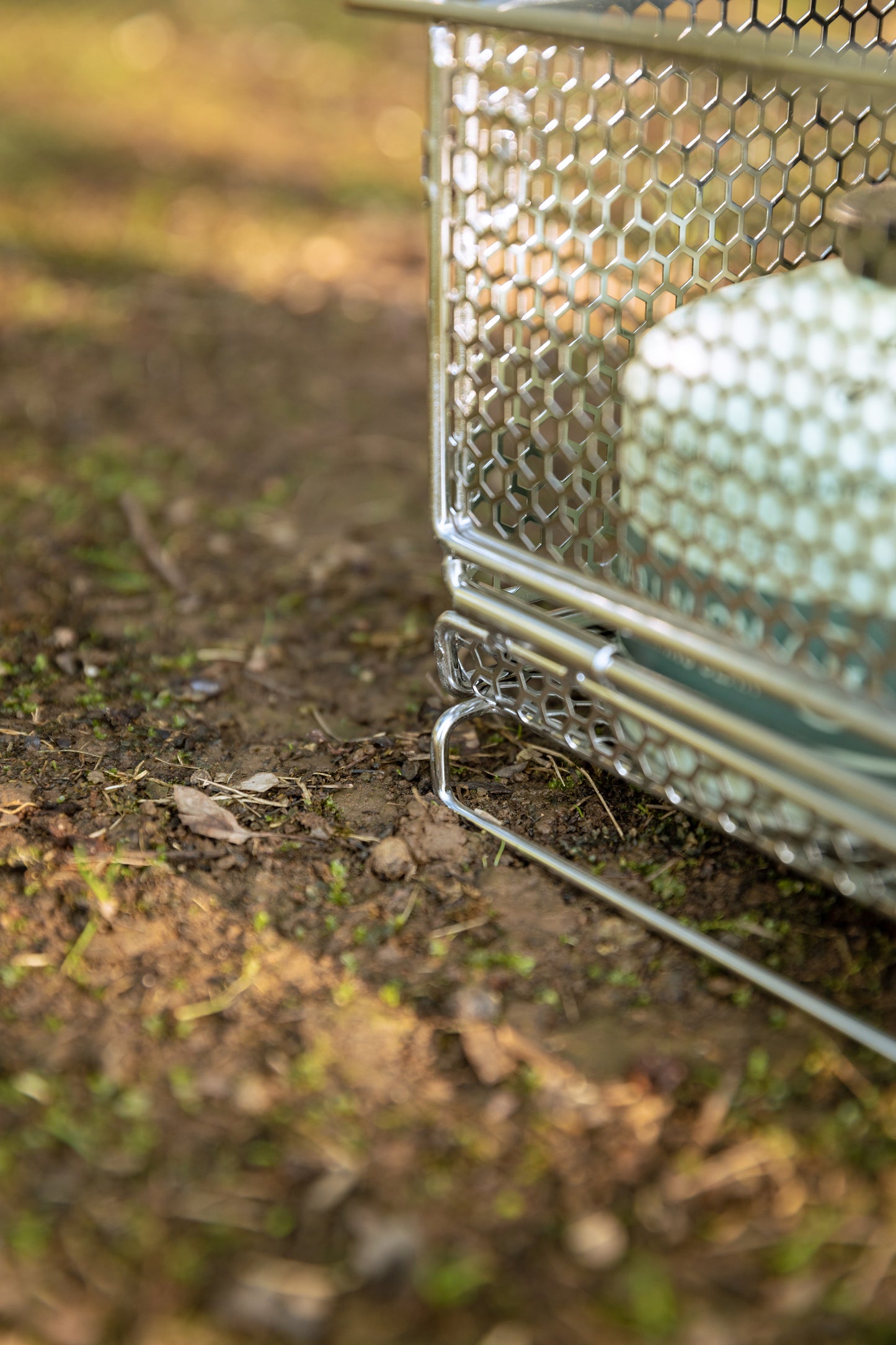 close up of a metal mesh basket with honeycomb design on a natural outdoor setting - camping gear - strong - stable - uk camping