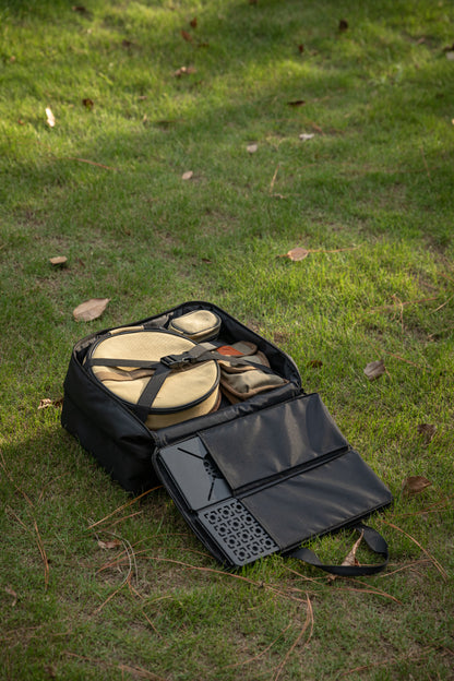 Black Nomadia CampStation Storage Bag with camping gear on a grassy ground - large storage camping bag for modular camping table 