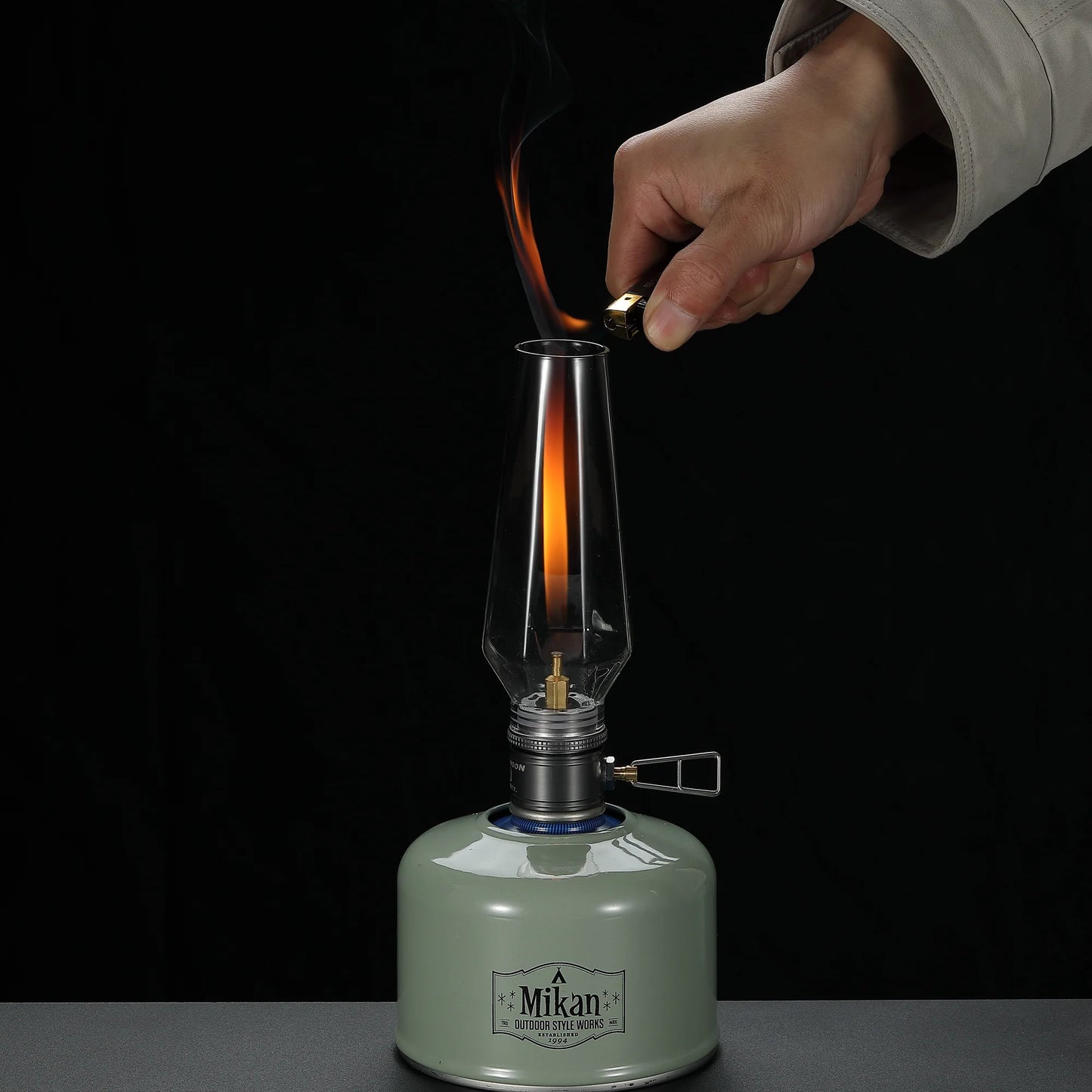 Person lighting a vintage-style gas lamp with a dark background - wildcamping - camping gear - uk camping - camping lamp with gas canister