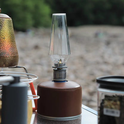 Vintage-style gas lamp with a brown base gas canister on a table outdoors - camping gear - wildcamping