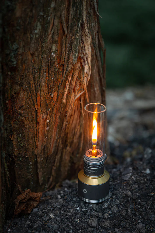 Flickering Nomadia Camping Light Candle-Style Gas Camping Lamp Set  against a tree trunk in a natural setting - camping with a fire - uk camping - atmospheric light 