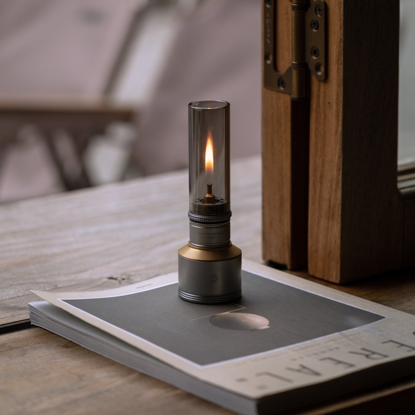 Portable Nomadia Camping Light Candle-Style Gas Camping Lamp Set with a flame on top of a book - camping with a fire - atmospheric light 