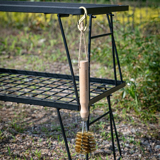 Nomadia Flamo 360° BBQ Grill Brush hanging on a modular table in natural background - camping gear - bbq grill accessory - uk camping