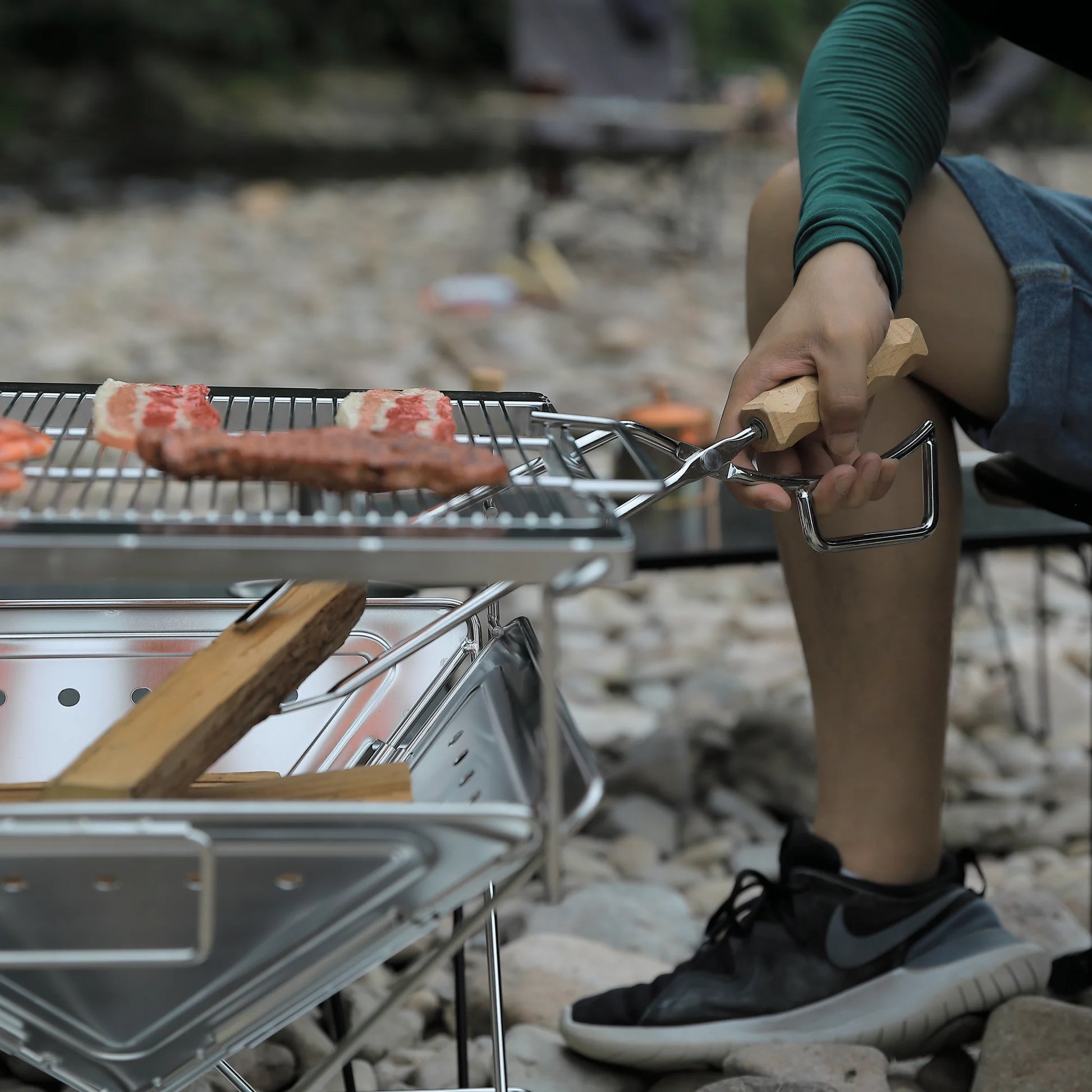 Person grilling food on Nomadia's Flamo Portable Folding BBQ Grill and Fire Pit - wildcamping - camping with a fire - uk camping