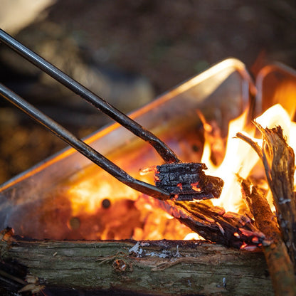 Precision Grip Fire Tongs holding a piece of wood over a campfire - camping with a fire - uk camping - glamping - wildcamping