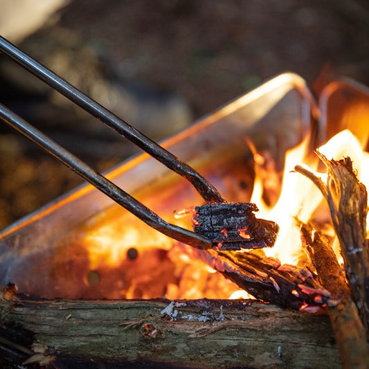 Precision Grip Fire Tongs holding a piece of wood over a campfire - camping with a fire - uk camping - glamping - wildcamping