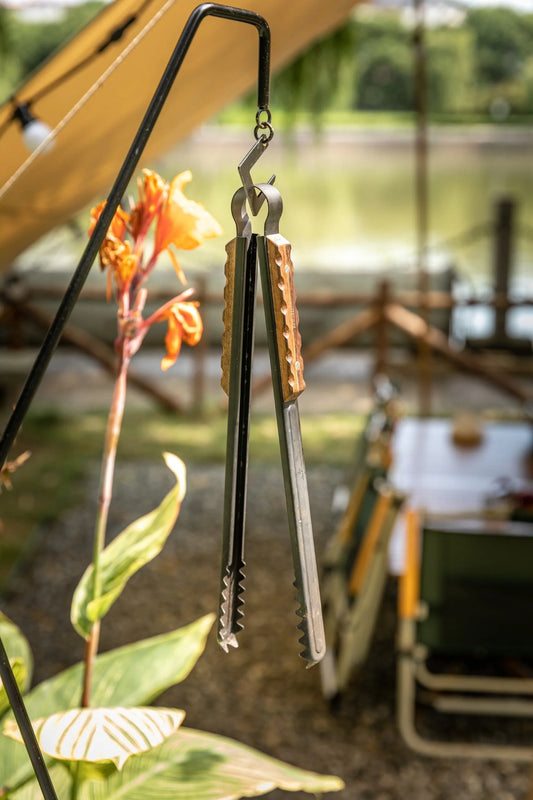 Nomadia Flamo Wood Handle Outdoor Heavy-Duty Outdoor Tongs hanging on a hook- camping gear - BBQ Grill accessory