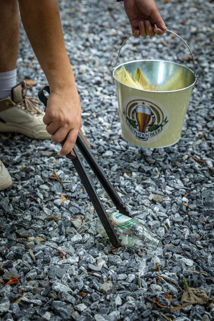 person using Nomadia Flamo Wood Handle Outdoor Tongs to pick up glass -camping gear - uk camping - camping essential
