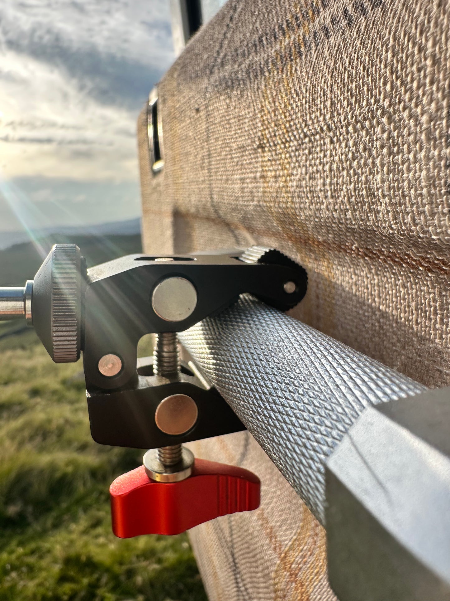 Close-up of a clamp attached to a textured surface Nomadia FlexArm Dual Clamp - multi-surface fit -camping and survival
