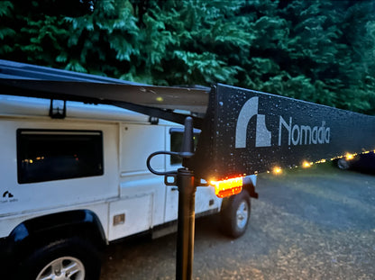 Nomada brand awning extended on a vehicle with trees - overlanding - wildcamping - aluminium awning - easy setup - fast setup awning - all weather durability