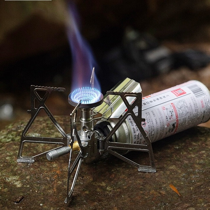 Portable gas stove with a lit flame on a rock surface - outdoor kitchen gear - outdoor cooking - portable powerful stove for outdoor use
