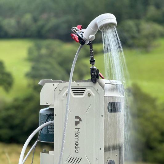 ThermoFLow - Portable heated shower system with Nomadia branding in use with running hot water in natural background - portable shower