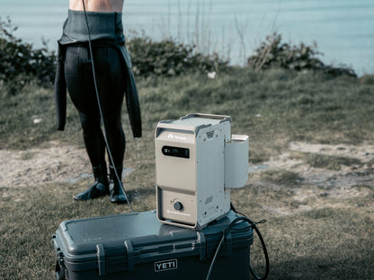 nomadia's thermoflow - a Portable heated shower system on a container outdoors. a man uses it to take a shower after surfing -camping gear - uk camping -outdoorsy