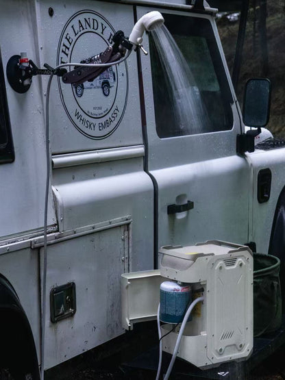 Nomadia ThermoFlow Portable Heated Shower next to a white van with a water hose attached to the side of the van for easy shower in the wild - wildcamping - uk camping - outdoor gear 