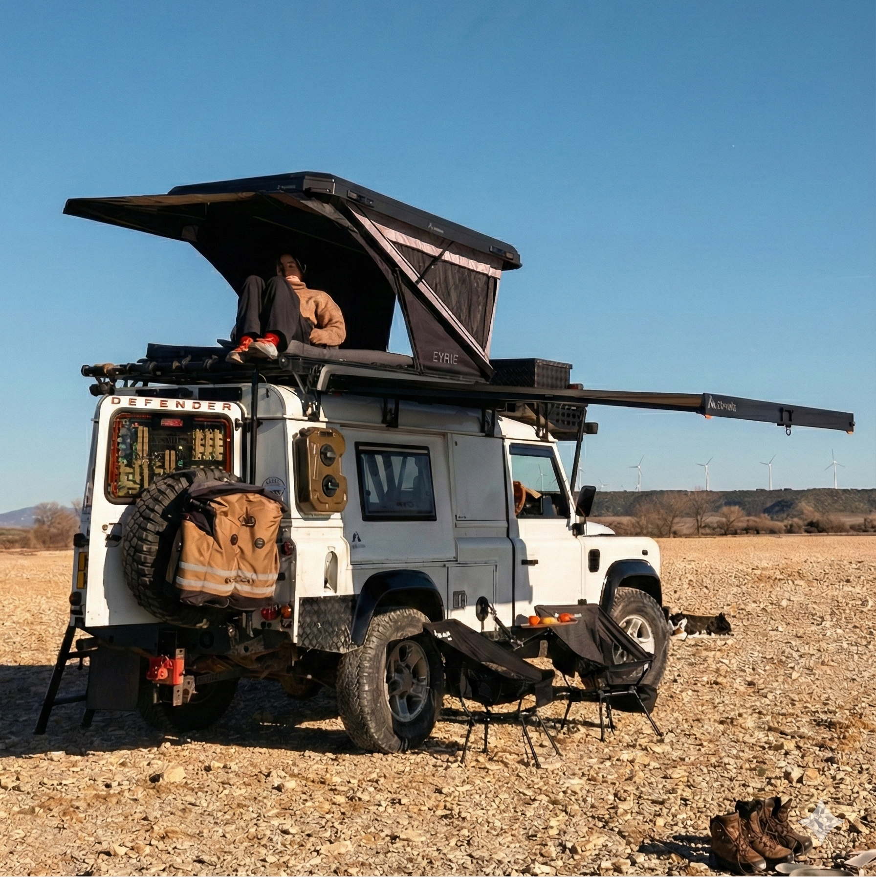 White off-road vehicle with a rooftop tent in a desert landscape