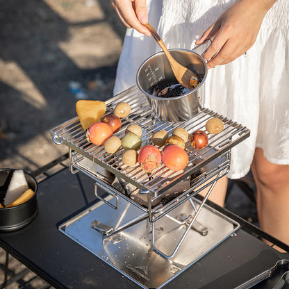 Nomadia's Flamo Portable Folding BBQ Grill and Fire Pit with food being cooked on a natural outdoor setting - wildcamping - camping with a fire - uk camping - glamping