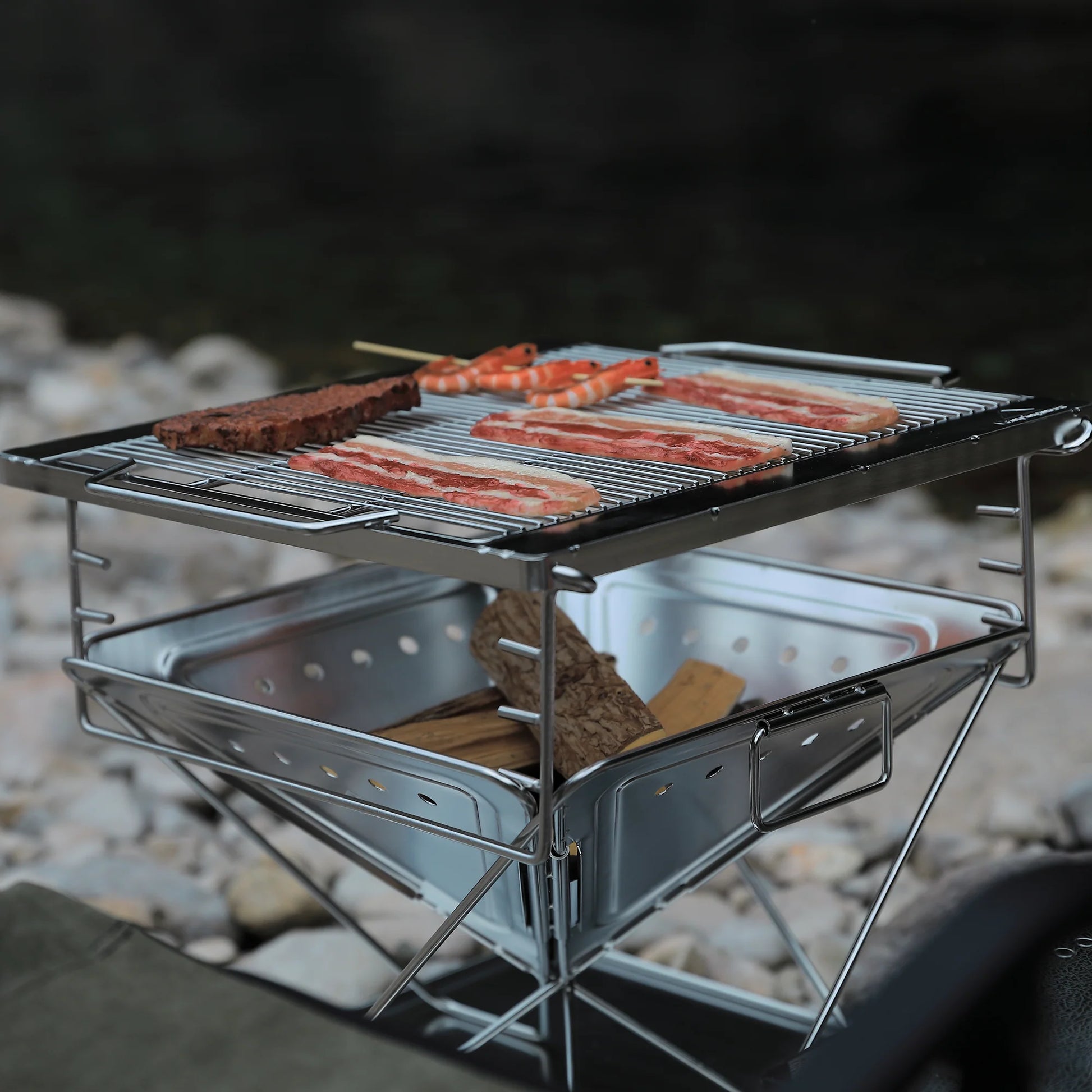 Nomadia's Flamo Portable Folding BBQ Grill and Fire Pit with food being cooked on a natural outdoor setting - wildcamping - camping with a fire - uk camping