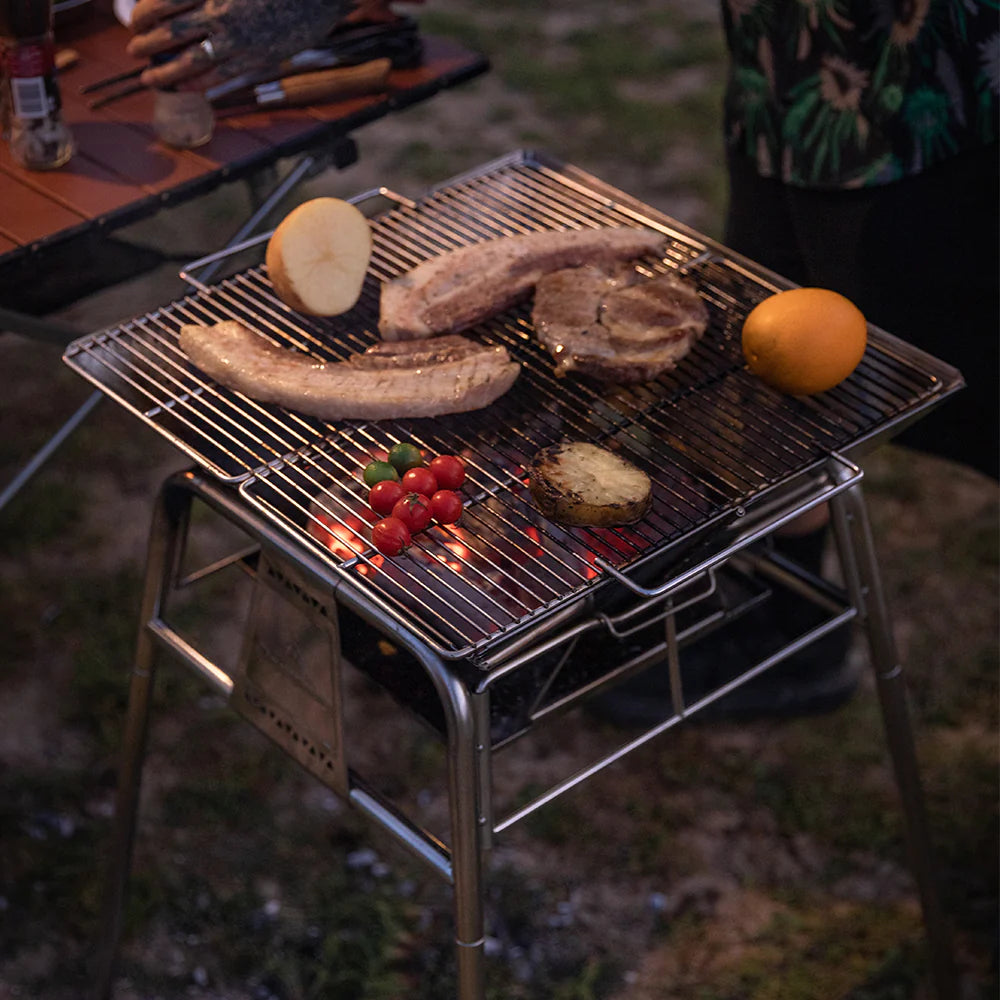 Nomadia's Flamo Portable Folding BBQ Grill and Fire Pit standalone cooking meat and vegetable in outdoor setting - wildcamping - camping with a fire - uk camping